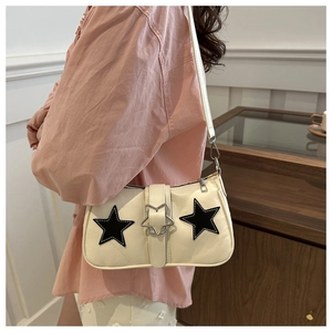 Detail of cream white underarm bag featuring black star patches and metal star buckle