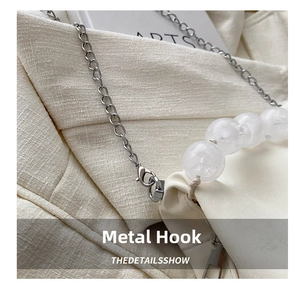 Detail of silver metal hook and white beaded chain on a soft PU cloud bucket bag