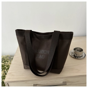 Close-up of dark brown canvas tote bag with FASHION BAG text and thick woven handles