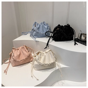 Detailed view of four pleated bucket bags in blue black pink and white on a clean display