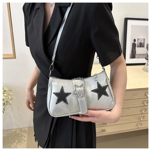 Détail du sac à bandoulière argenté avec étoiles noires et boucle en métal sur modèle