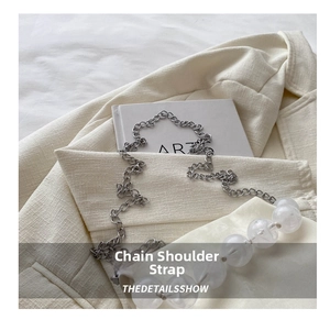 Detail of elegant silver metal chain strap with large clear crystal beads on tweed fabric