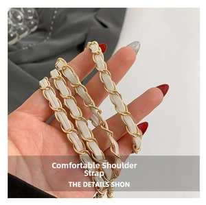Detail of white leather interwoven with golden metal chain strap on a small bag