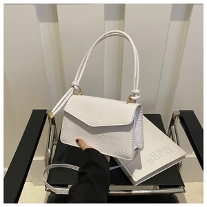 Detail of white crocodile embossed crossbody bag with golden hardware and slim shoulder strap