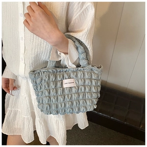 Detail of light blue quilted tote bag featuring a Love Fashion woven label and texture