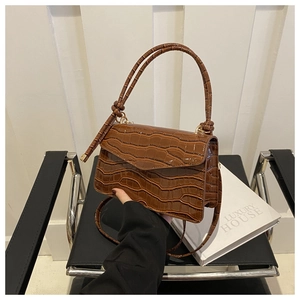 Detail of caramel crocodile pattern shoulder bag with golden hardware and top handle