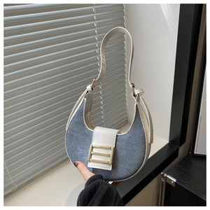 Detail of blue denim and white leather crescent hobo bag with gold metal buckle