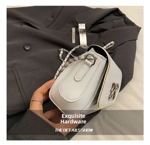 Close-up of a white quilted crossbody bag with silver bow buckle and metal chain strap