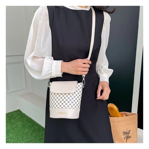 Vue détaillée du mini sac seau avec motifs géométriques bleus et logo doré lettré