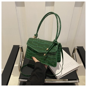 Detail of dark green crocodile texture on a mini square bag with polished finish and straps