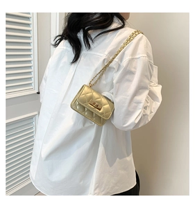 Detailed view of mini gold quilted chain bag with twist lock on shoulder for styling
