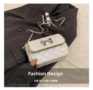 Close-up of white quilted crossbody bag with silver bow clasp and chain strap