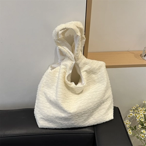 Chic off-white pleated tote bag with bubble texture on a leather sofa