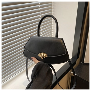 Détail d'un sac à main noir en forme d'éventail avec boucle dorée sous lumière naturelle