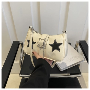 Détail du sac sous le bras blanc cassé avec patchs d'étoiles noires et boucle argentée