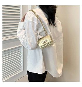 Detailed back view of gold quilted chain strap crossbody bag on a female model