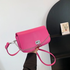 Minimalist magenta crossbody bag with silver chain and twist lock on a shoulder strap