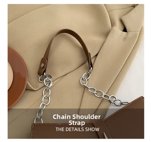 Détail de la poignée en cuir marron et de la chaîne en métal argenté du sac à bandoulière