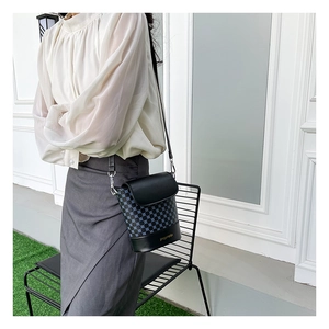 Détail du sac seau bandoulière en cuir noir et tissu avec motif géométrique bleu