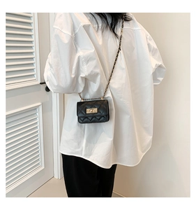 Detail of black quilted leather crossbody bag with gold metal twist lock and chain strap