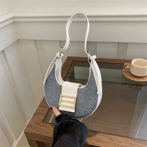 Blue denim hobo bag with white trim and large gold buckle in a lifestyle setting