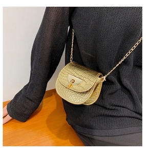 Detail of gold crossbody bag with crocodile texture and metallic semi-circle buckle clasp