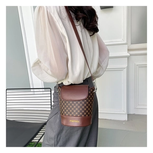 Détail d'un sac seau vintage marron à carreaux avec finitions en cuir lisse et bandoulière