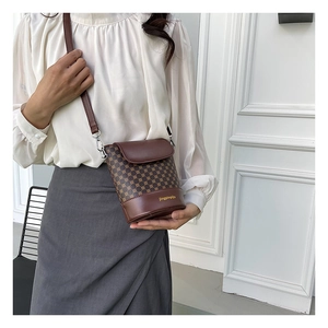 Détails d'un sac seau vintage avec garniture en cuir marron porté par un mannequin