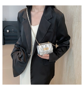 Detail of silver quilted leather mini bag with gold twist lock and chain strap on model