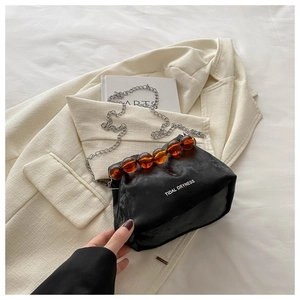Detail of black soft leather bucket bag featuring amber beads and silver chain strap