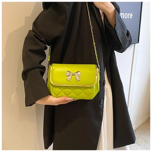 Bright green quilted chain crossbody bag with silver bow detail on a fashion model