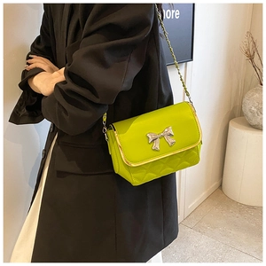 Detail of lime green quilted bag with silver bow accent and metal chain strap