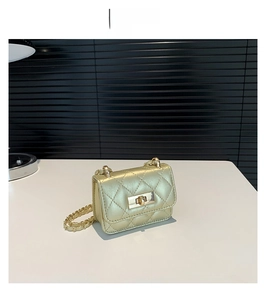 Detail of gold quilted mini crossbody bag with metal twist lock and elegant chain strap