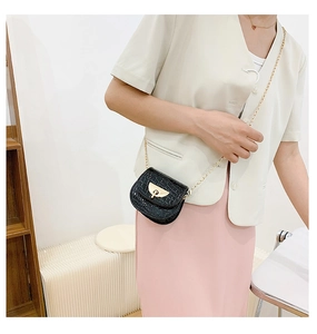 Detail of black faux leather crossbody bag with crocodile pattern and golden chain