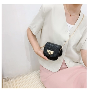 Mini black crocodile embossed saddle bag with gold lock and chain on female model