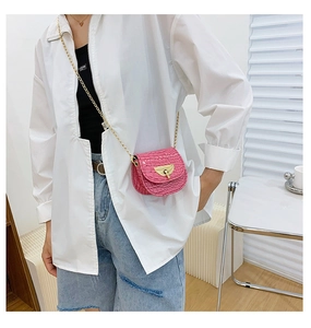 Close-up of fuchsia mini saddle bag with crocodile texture and gold chain strap