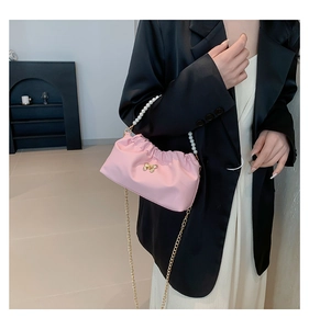 Dettaglio borsa a nuvola plissettata rosa con manico di perle e fibbia a farfalla oro
