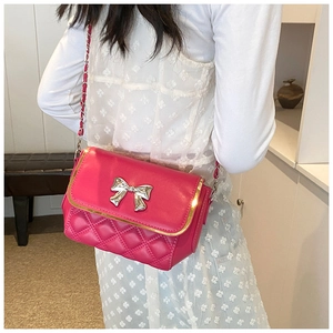 Close-up of fuchsia quilted crossbody bag with gold bar and silver metal bow detail