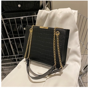 Detail of black crocodile texture leather bag with elegant gold metal chain strap