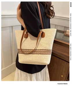 Detail of woven straw tote bag with brown leather handles and lace trim in a home setting