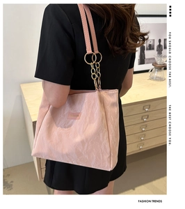Dettaglio della borsa tote rosa testurizzata con catena dorata e logo in metallo moda