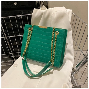 Close-up of green crocodile pattern PU leather with a gold chain strap detail