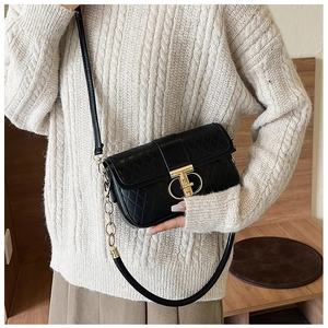 Detail der schwarzen Stepptasche mit goldener T-Schnalle und elegantem Kettenriemen