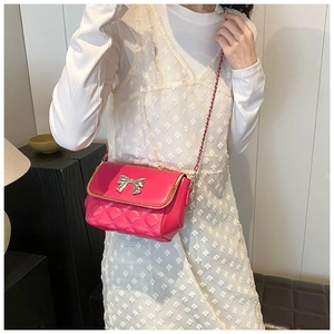 Close-up of bright pink quilted crossbody bag with silver bow buckle and chain strap