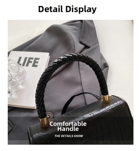 Close-up of black crocodile pattern leather handbag with thick braided handle and gold hardware