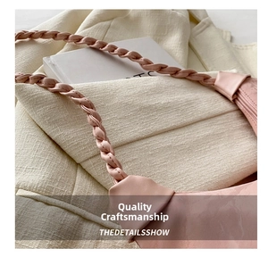 Detail showing the woven shoulder strap and fine stitching on the pink leather bag