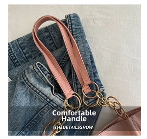 Dettaglio del manico in pelle rosa con anelli dorati e catena su una grande borsa