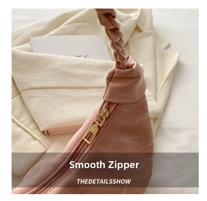 Detail of premium smooth golden metal zipper on a pink pleated crossbody bag