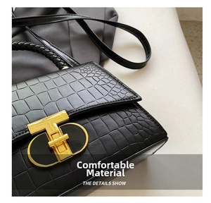 Detailed close-up of a black crocodile pattern handbag with a golden T-shaped metal lock