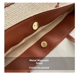 Detail of magnetic snap closure and leather trim on beige woven straw tote bag